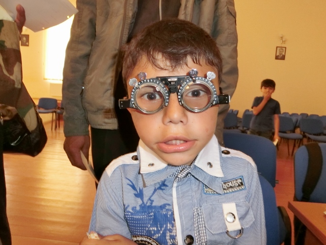 視力チェック後に仮枠でトライアルする遠視性乱視の男の子